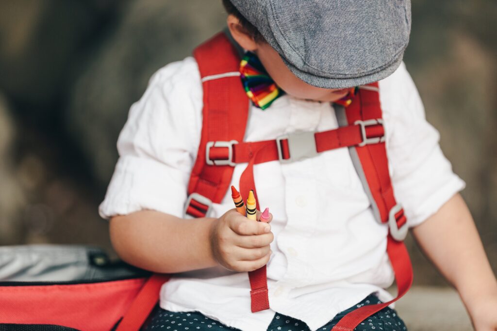 A little boy with a hat holding crayons in one hand