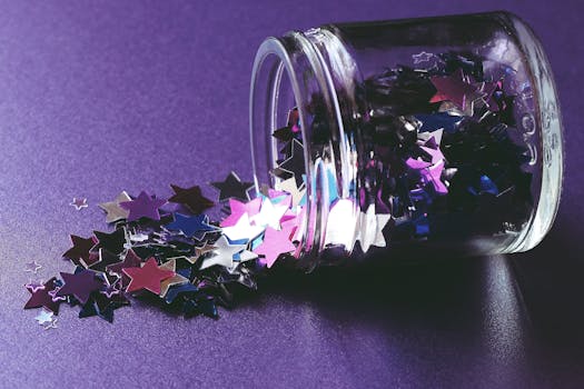 Close-up of colorful star-shaped confetti spilling from glass jar on purple surface. Ideal for creative and festive themes.